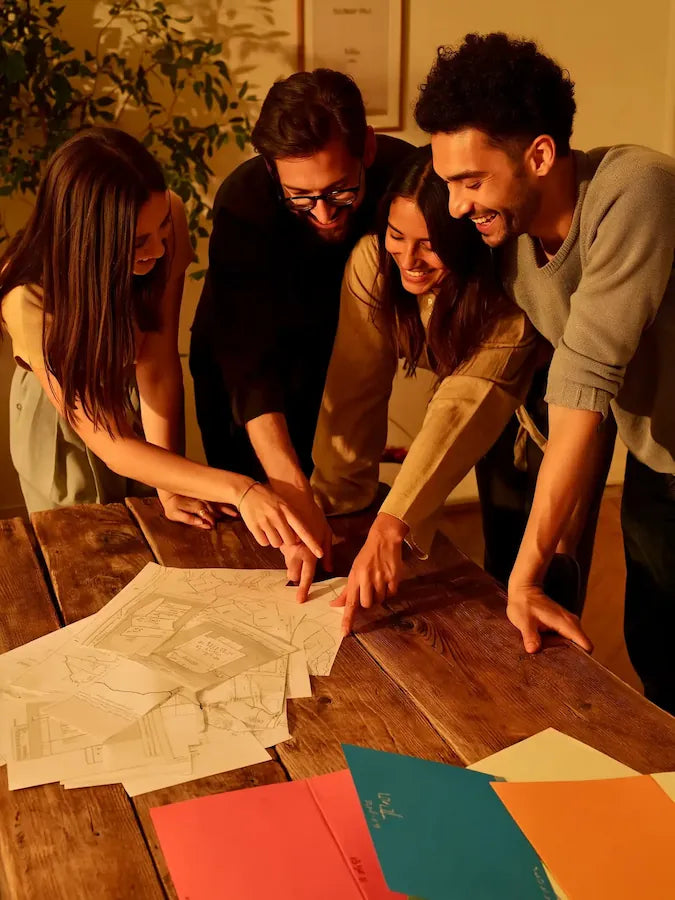 Group of friends gathered around a table solving clues in a detective mystery board game - perfect Christmas gift idea.