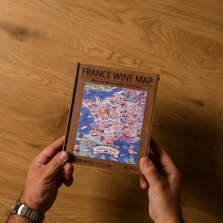Hands assembling the France Wine Map 200‑piece birch wooden puzzle.
